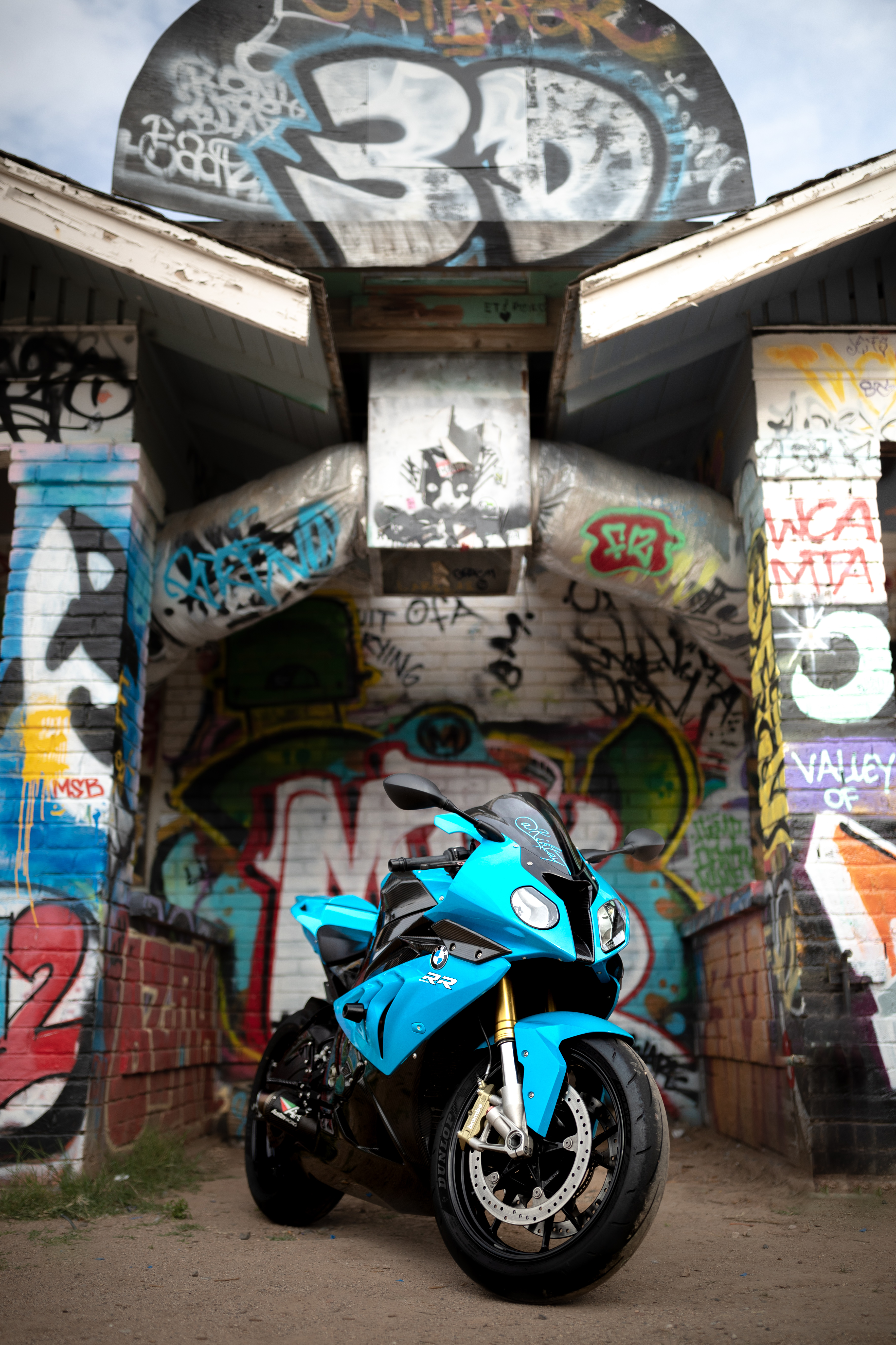 Blue BMW RR motorcycle in front of a graffiti-covered building