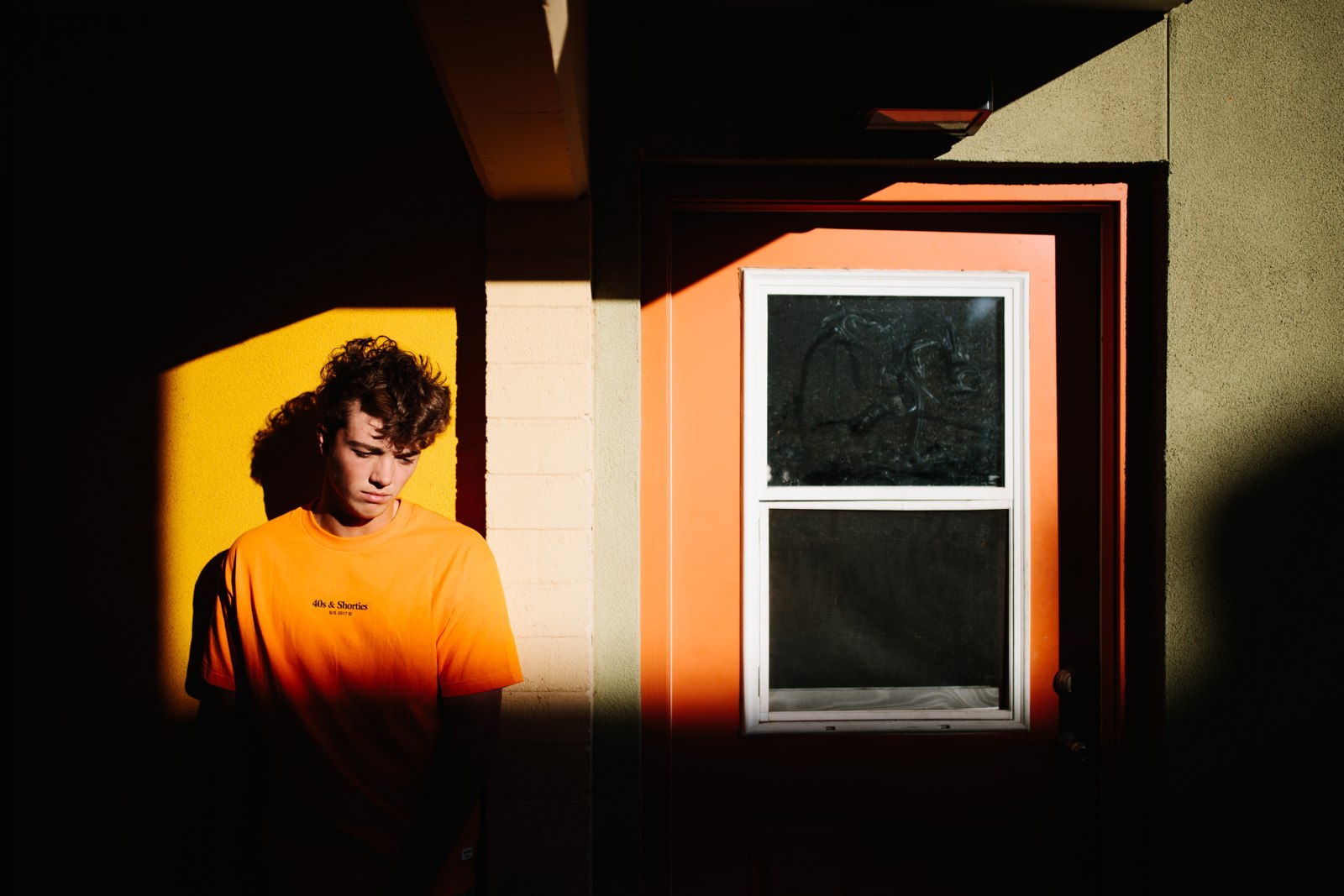 Portrait in an orange shirt framed by light and shadow