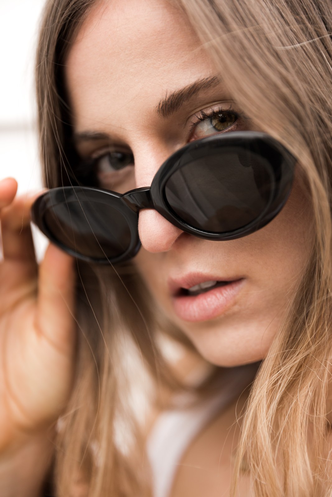 Close-up portrait of a woman adjusting sunglasses