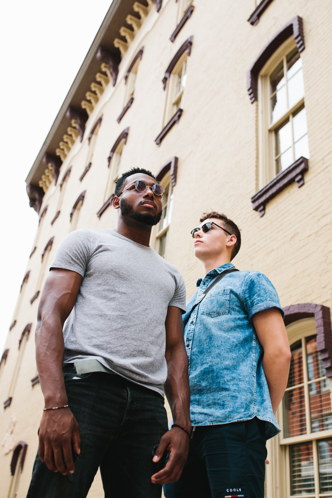 Two men wearing sunglasses beside a building