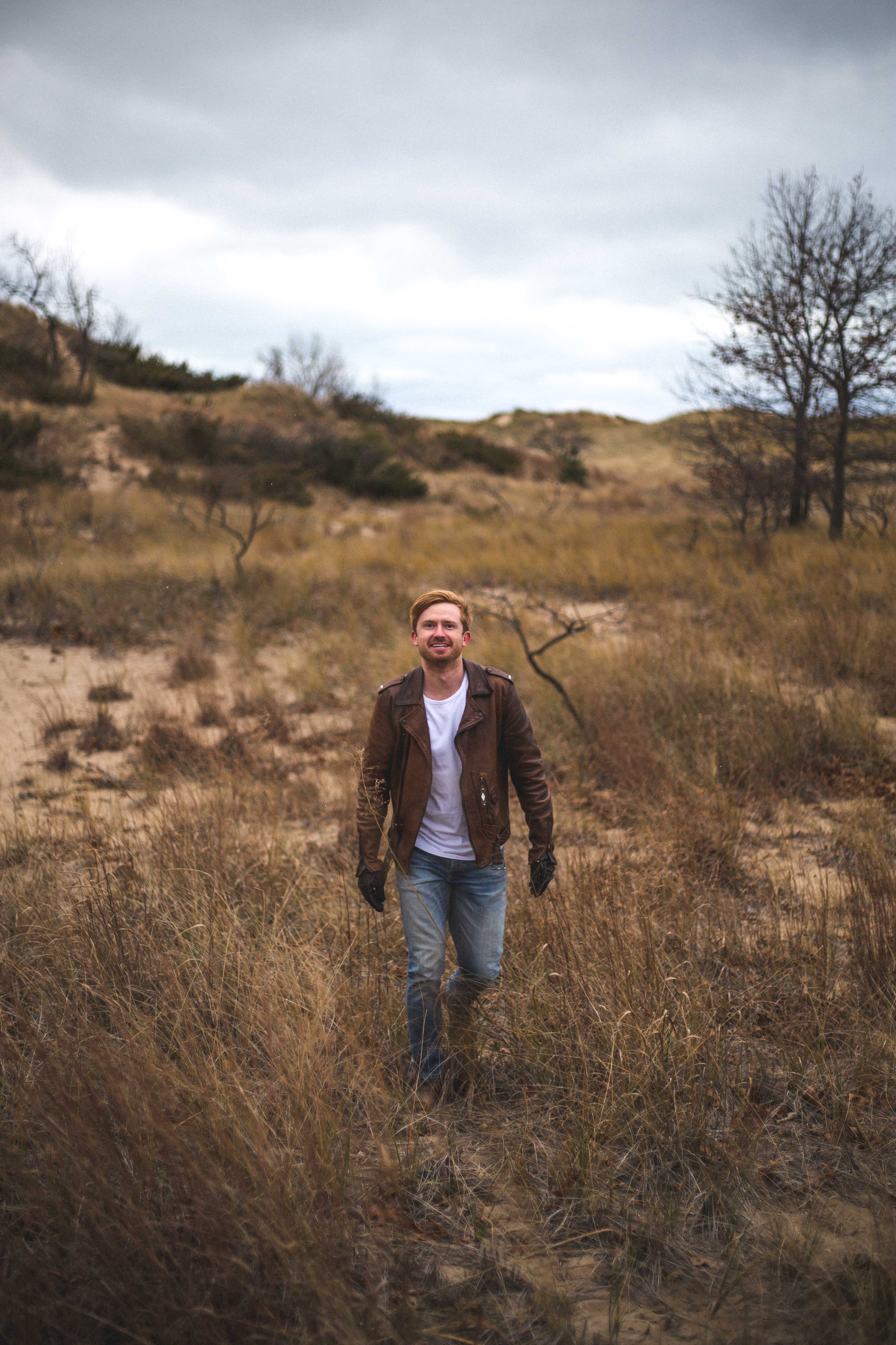 Outdoor portrait of a man walking through a grassy field