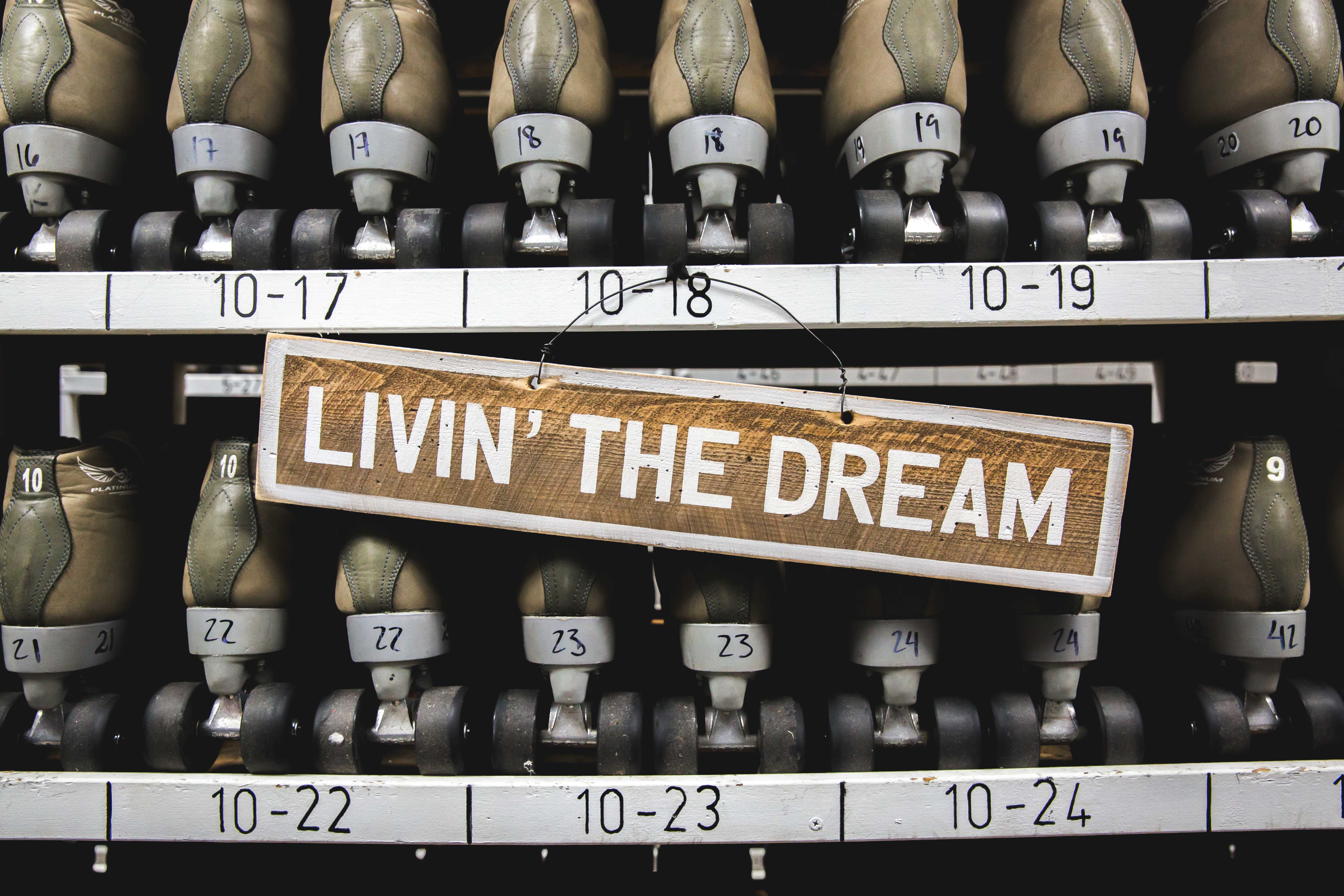 Weathered Livin’ the Dream sign in front of vintage roller skates